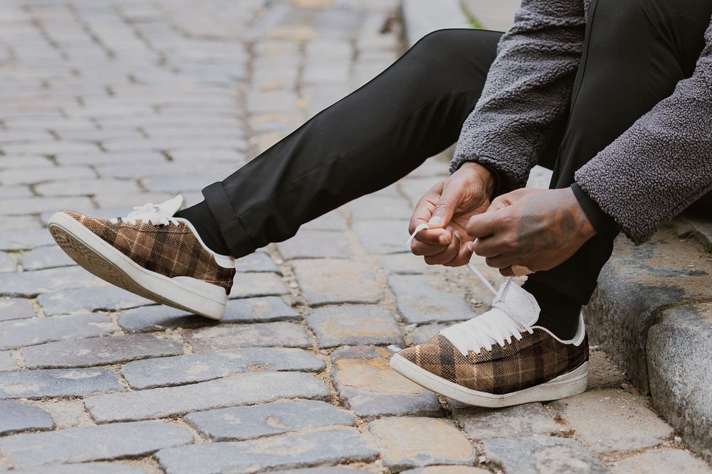 Man tying shoelaces on cobblestone street 