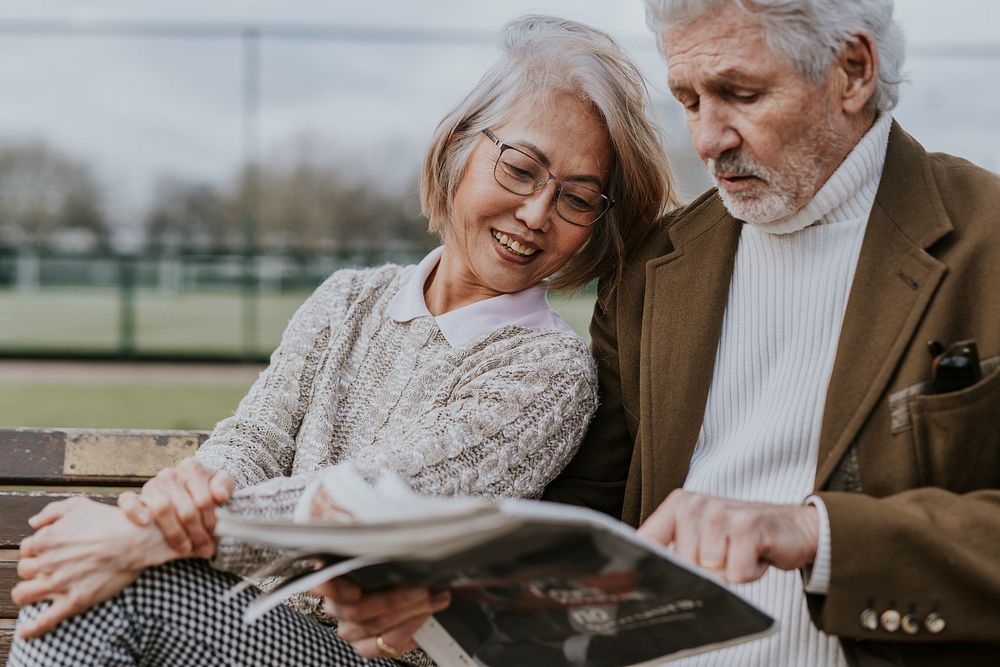 Diverse senior couple reading the news outdoors