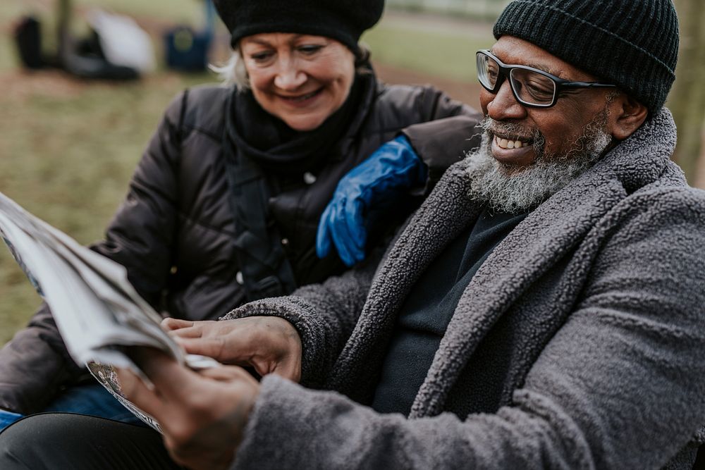 Couple reading newspaper on park bench