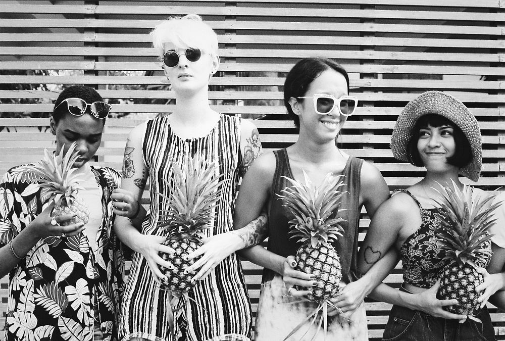 Group of diverse women standing holding pineapples