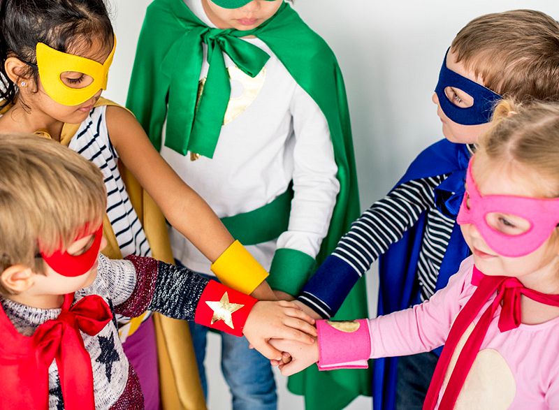 Kids in superhero costumes with all hands in