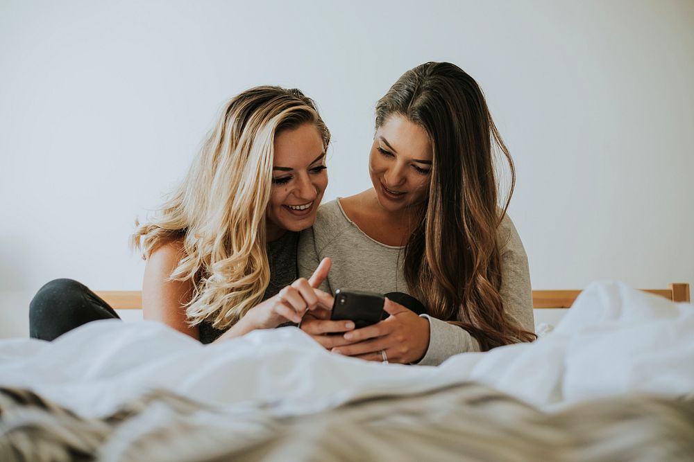 Girls playing with a phone in bed