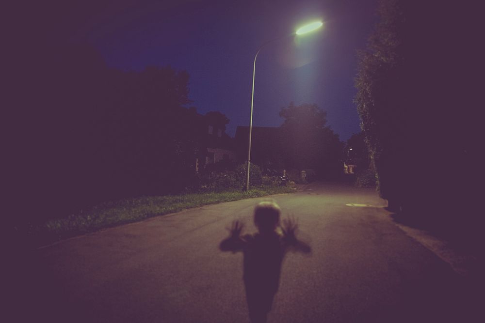 A lone child walking down the street at night