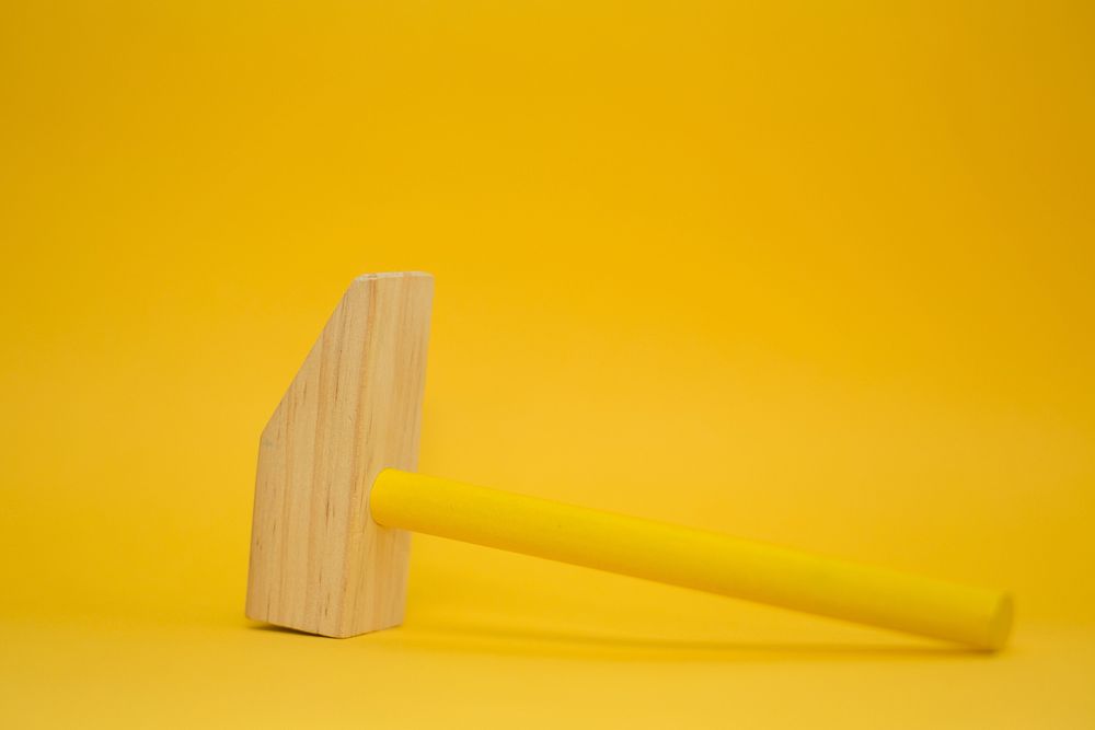 Wooden mallet on yellow background