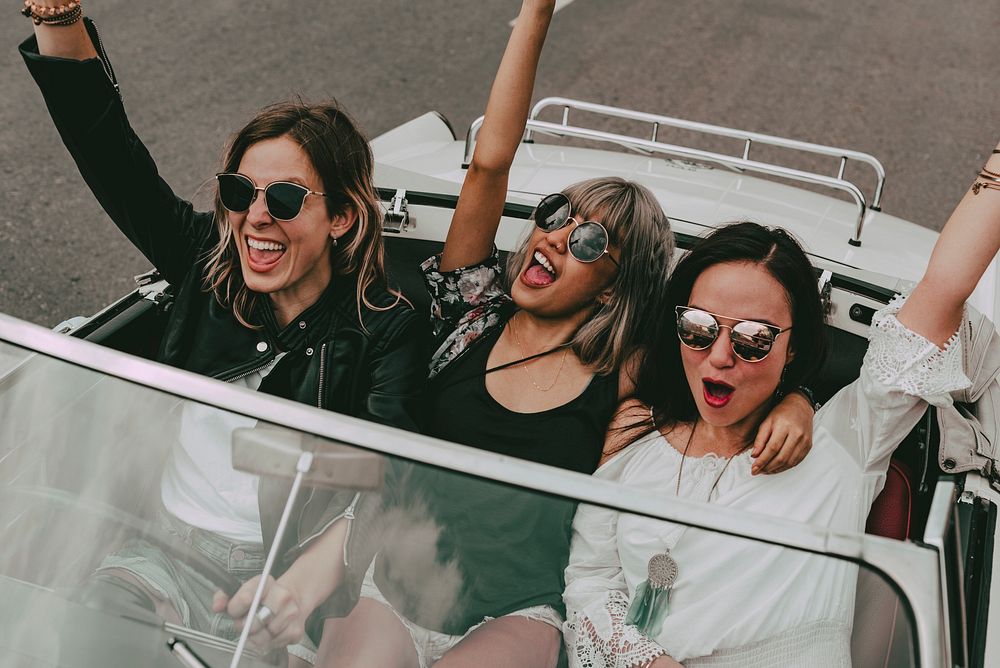 Boho girls on convertible car, summer road trip to the festival
