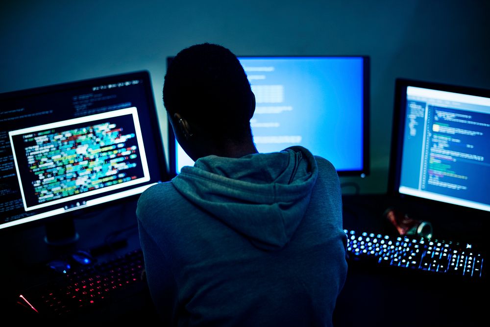 Hacker working on computer monitors