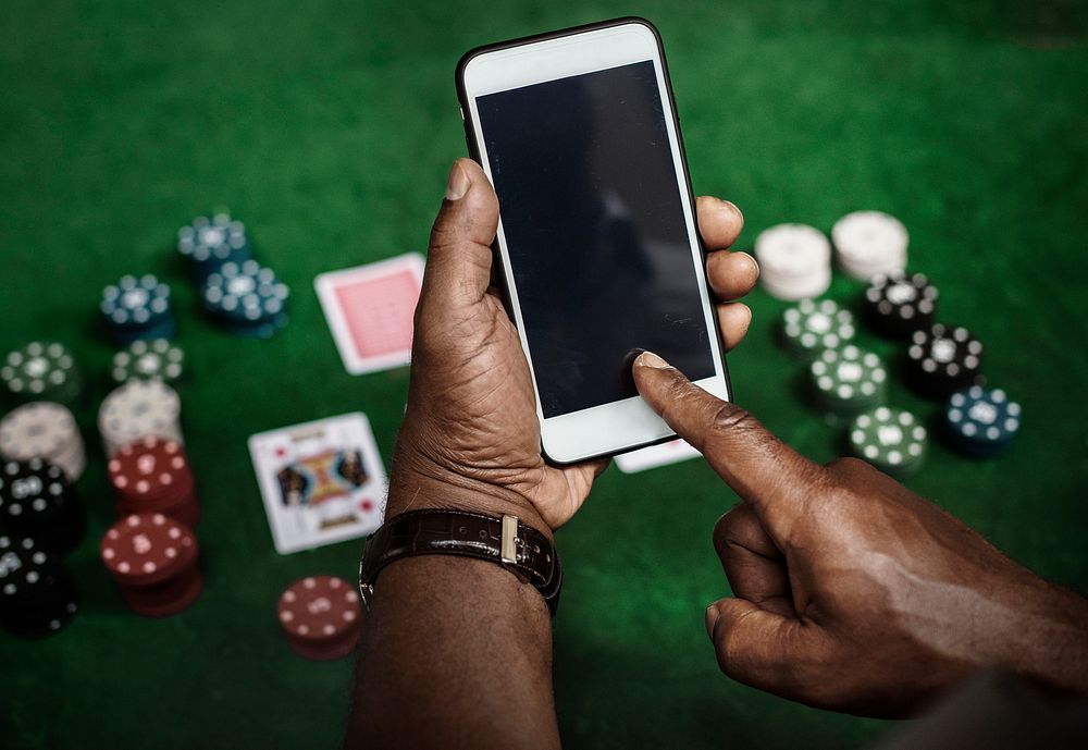 Hands using mobile phone with casino coins in the background