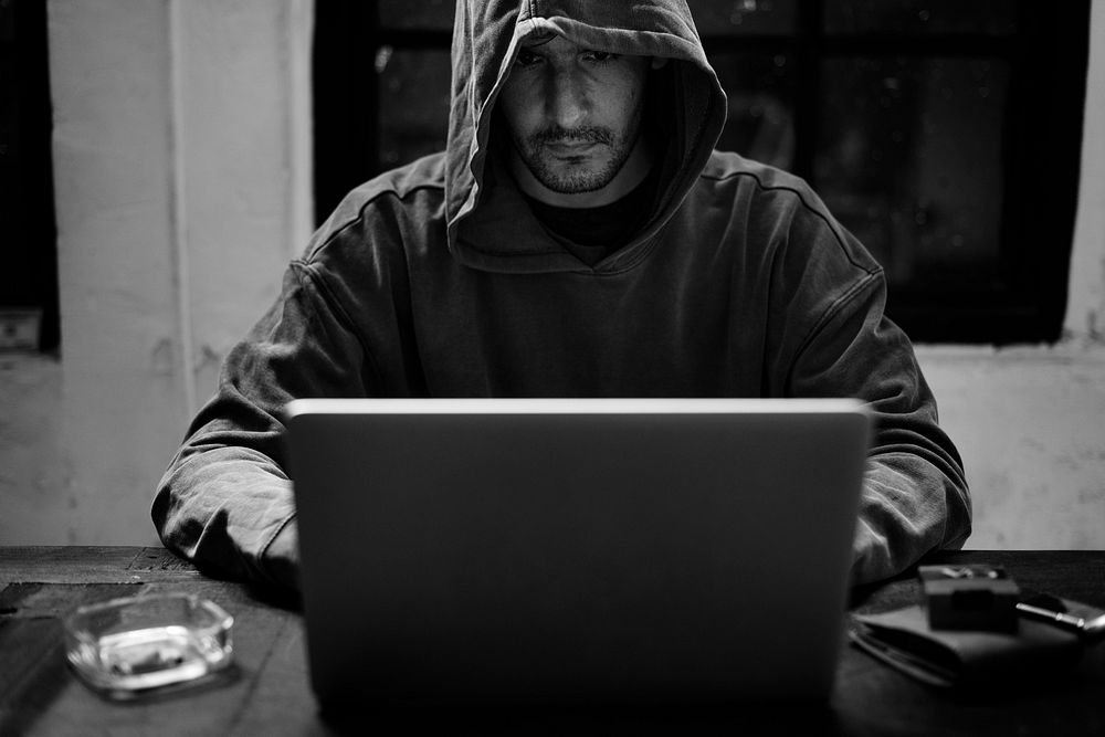 Guy in a hoodie hacking in his computer