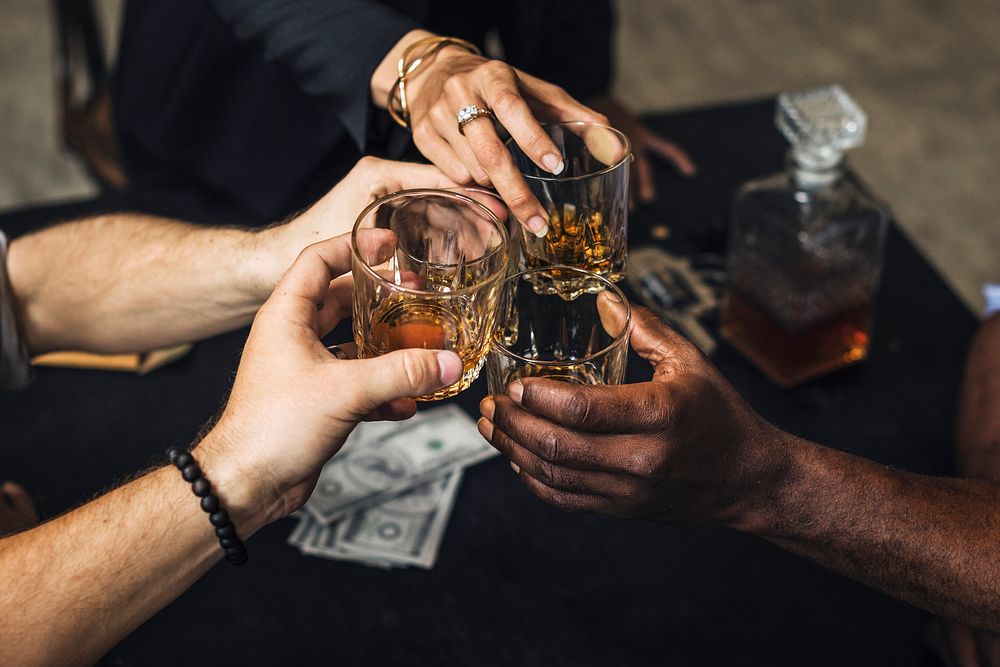 Diverse hands clinking alcohol glasses 