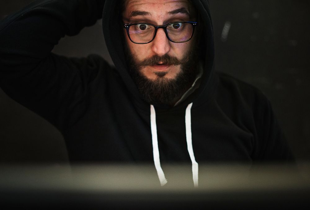 Hacker in a hoody working on computer