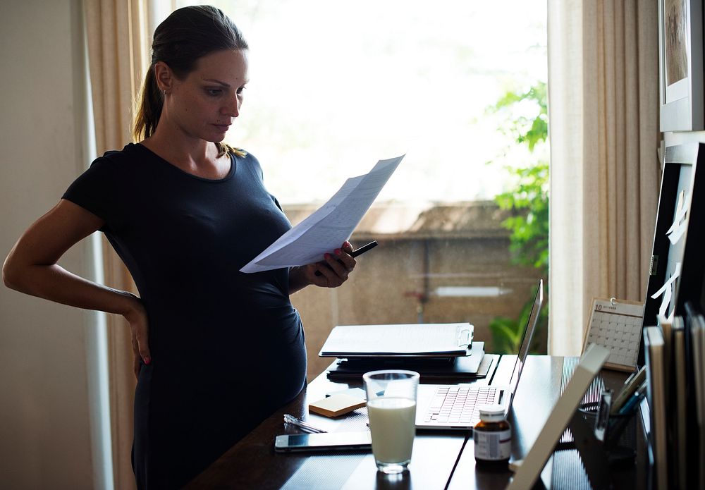A pregnant woman reading notes and drinking milk