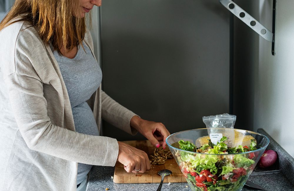 Pregnant woman is cooking salad