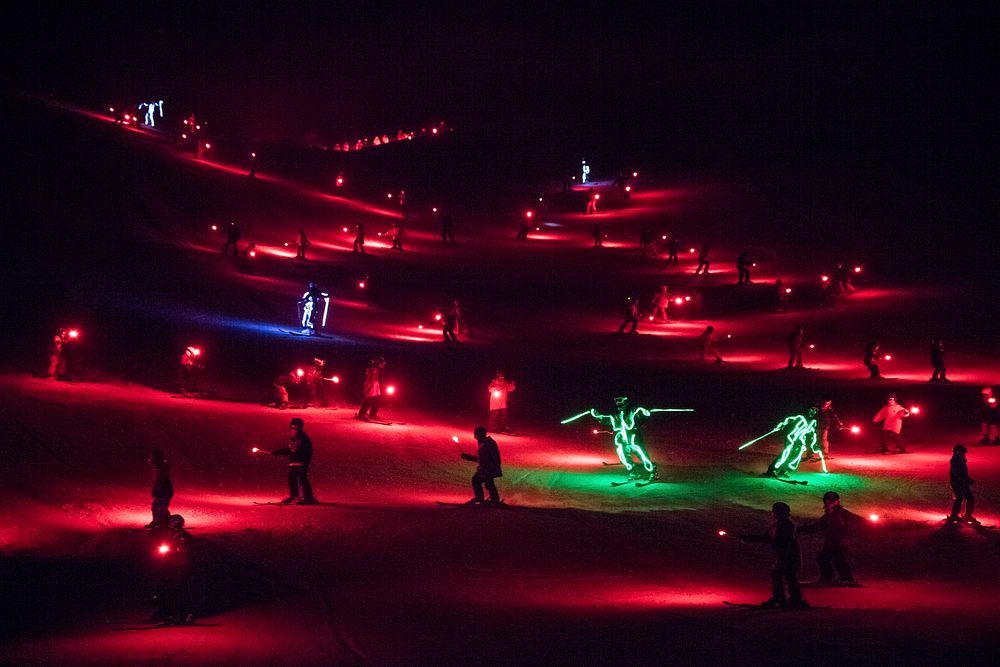 Colorfully attired skiers and snowboarders carrying flares and LED (light-emitting-diode) lights descend Howelsen Hill en…
