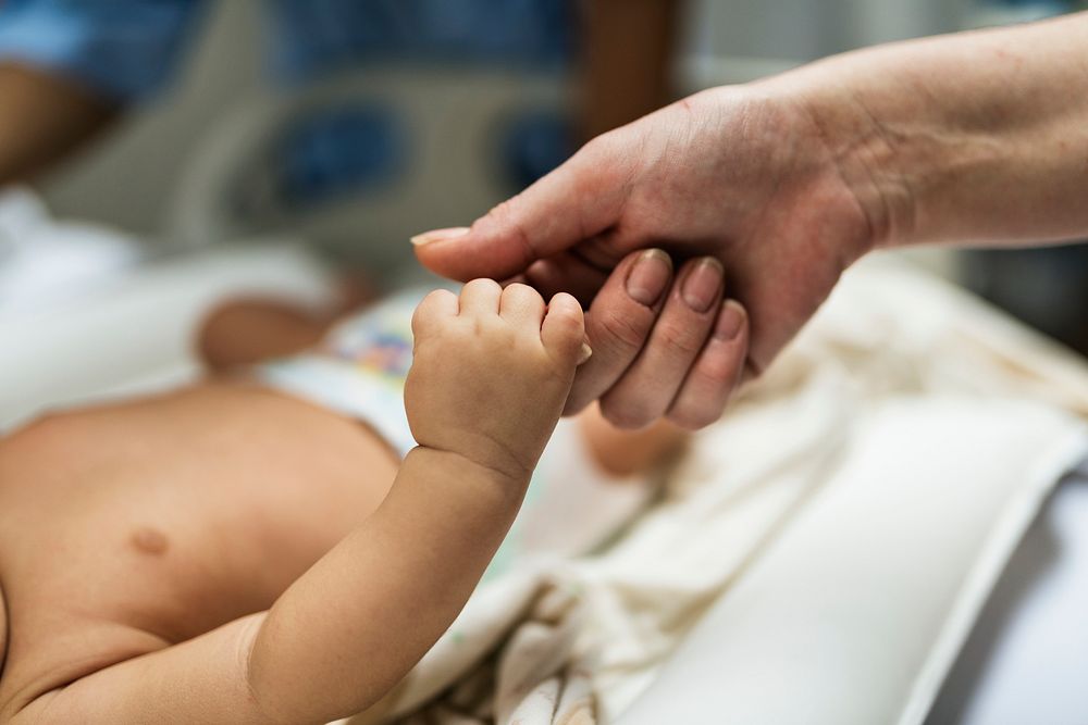 Newborn baby holding an adult hand