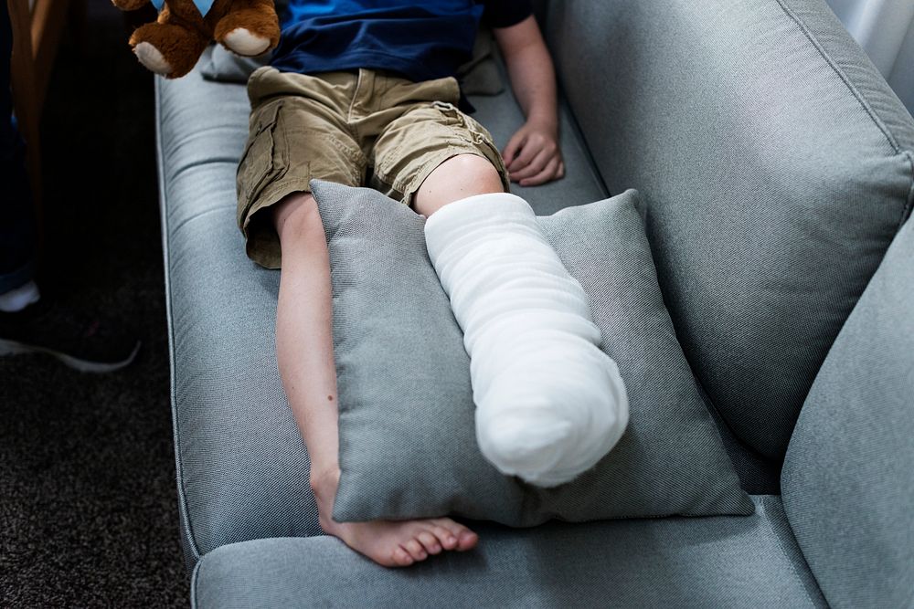 Kid with injured leg is sitting on the couch