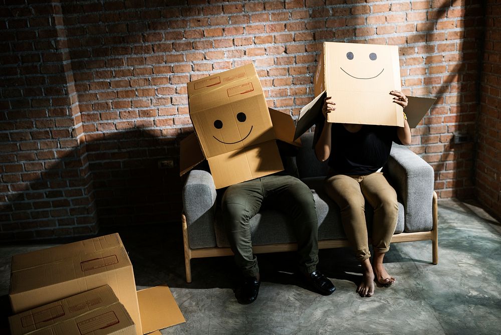 Couple sitting together with heads in boxes