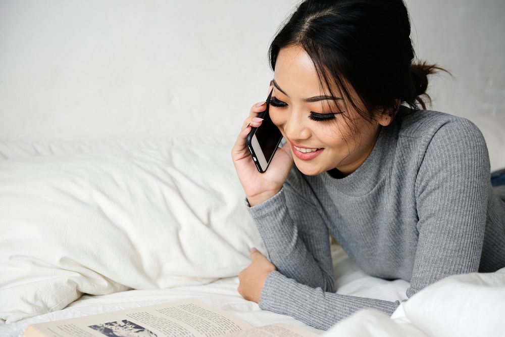 Woman Using Mobile Phone on a Bed