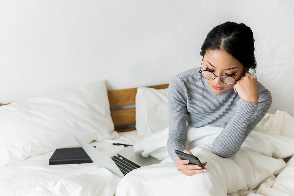 Woman is using mobile on the bed