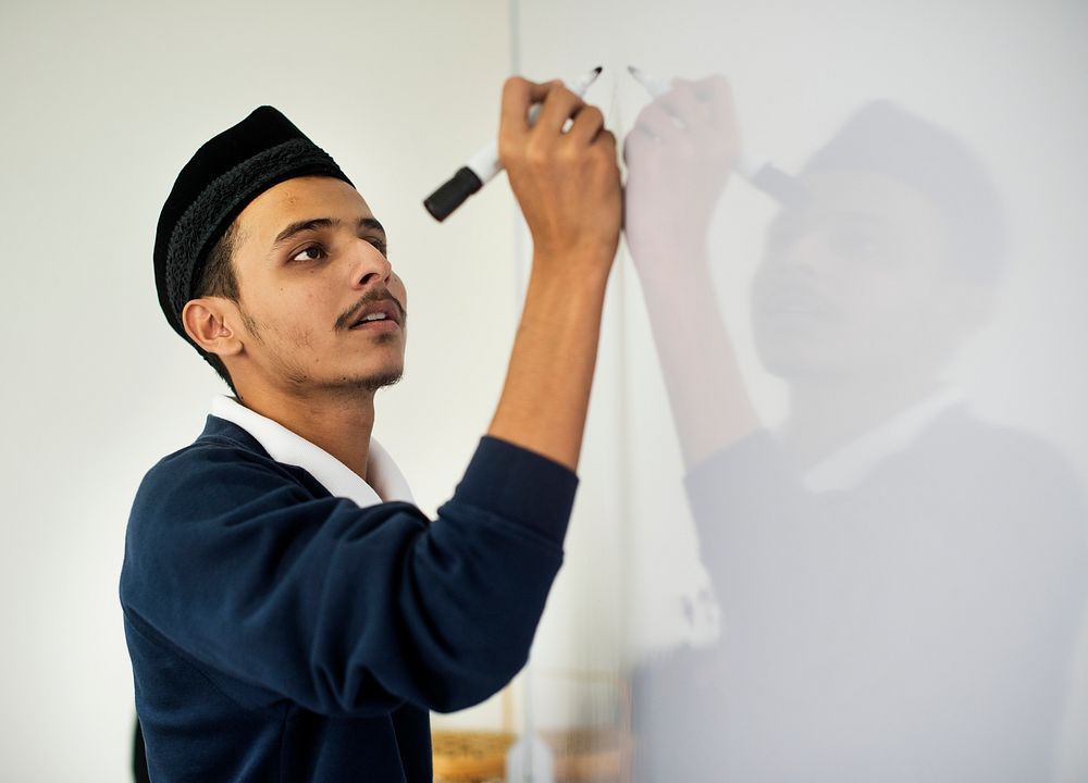 Young muslim man is writing a white board