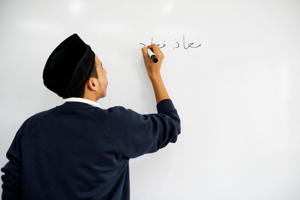 Young muslim man is writing a white board