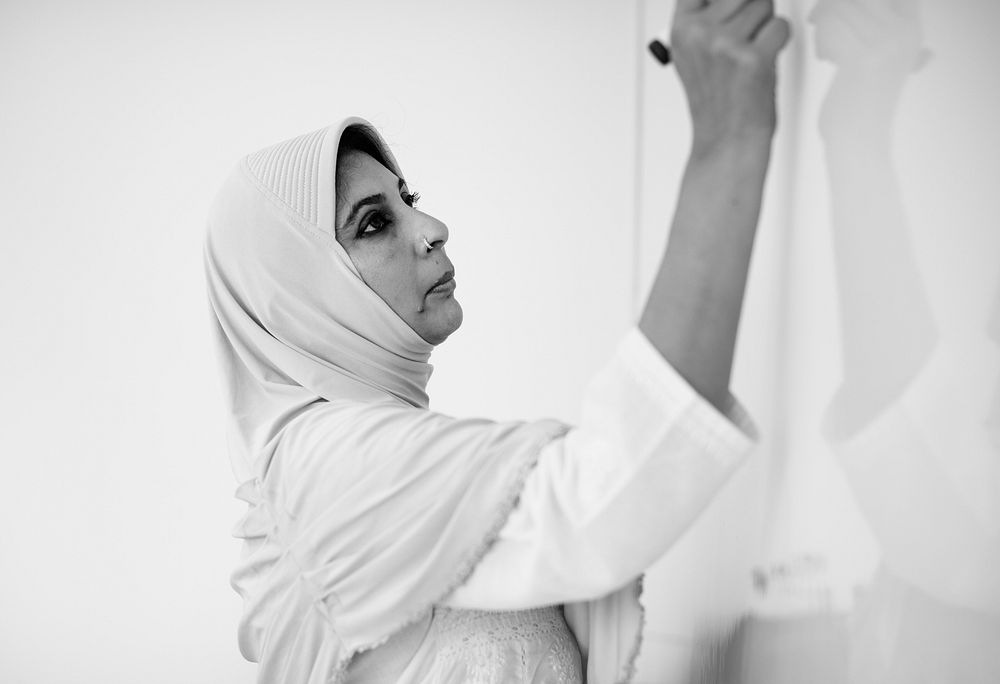 A Muslim teacher is writing a white board