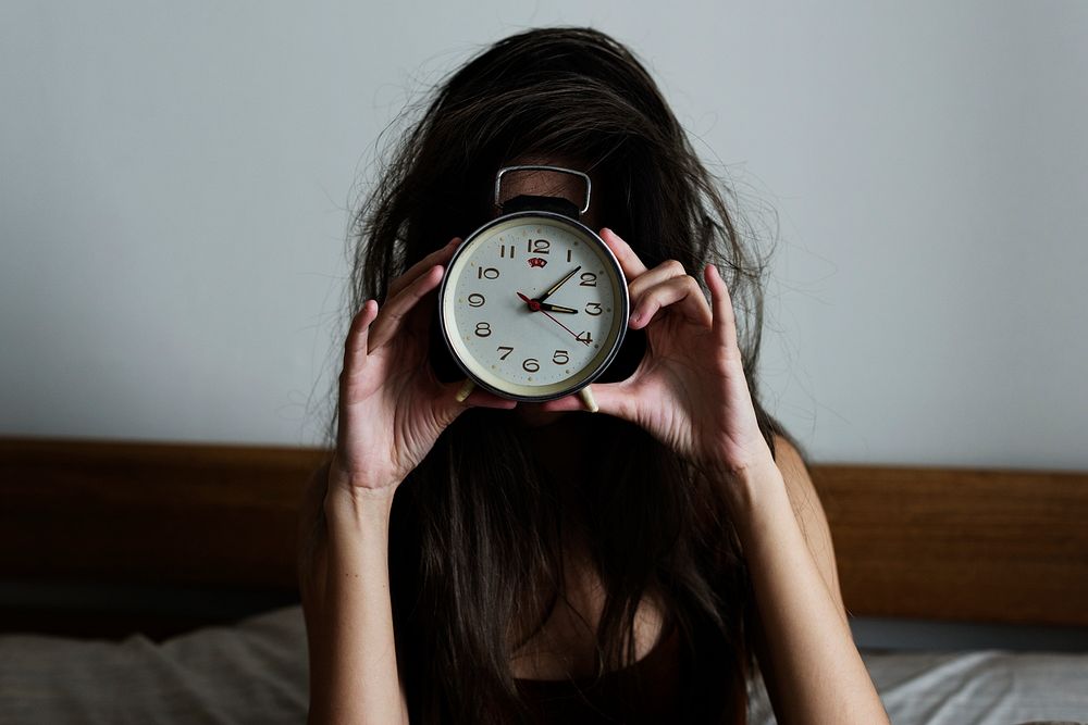 Girl holding a clock in front of her face