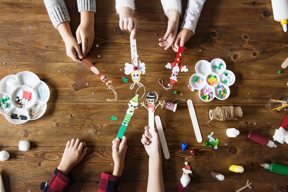Kids' hands holding Christmas character decorated popsicle sticks