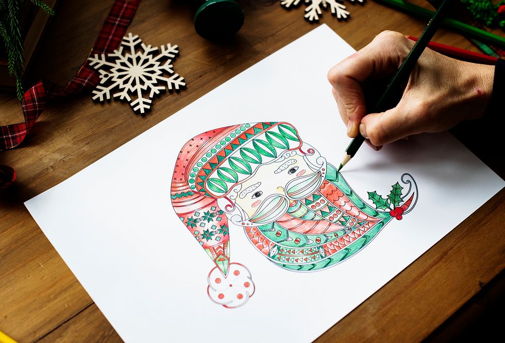 A person drawing a colorful Santa Claus' face