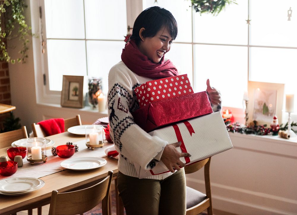 An Asian woman carrying Christmas gift boxes