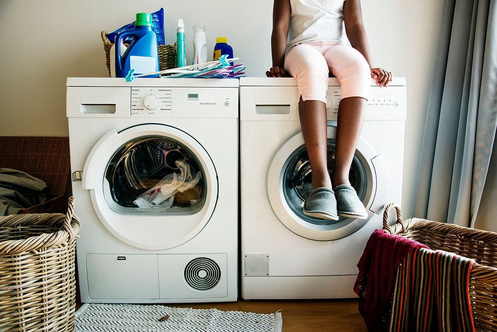Young teen girl waiting for clothe to be washed from washing machine