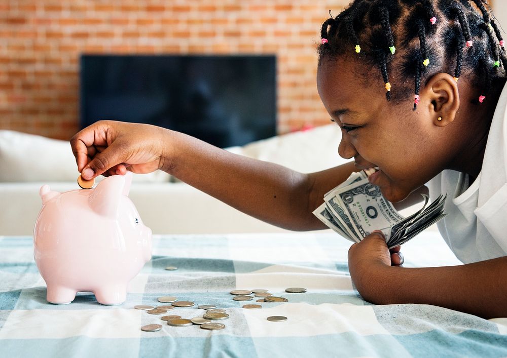 Black girl collecting money to piggy bank
