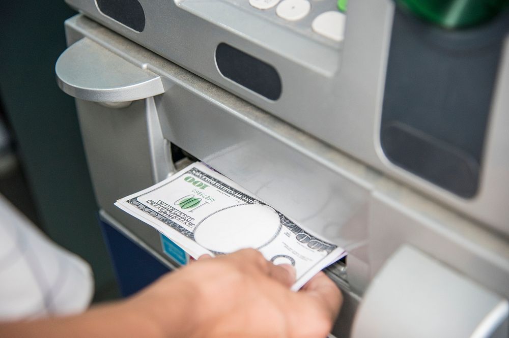 Closeup of a hand getting money from an ATM