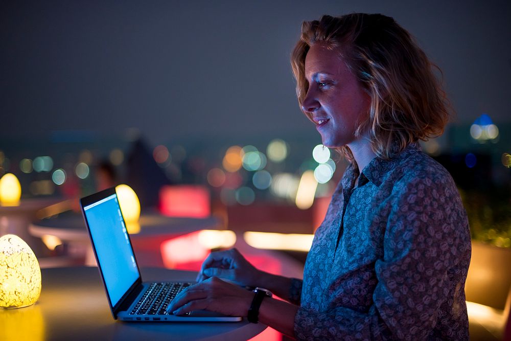 Woman working on a laptop at a rooftop bar