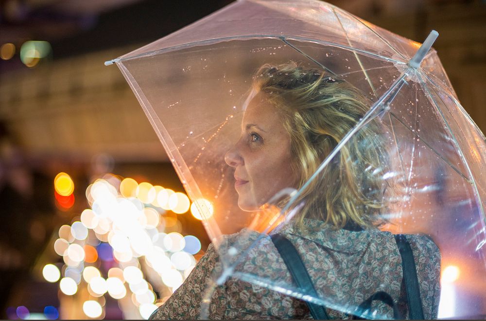 Blond woman taking cover under her umbrella