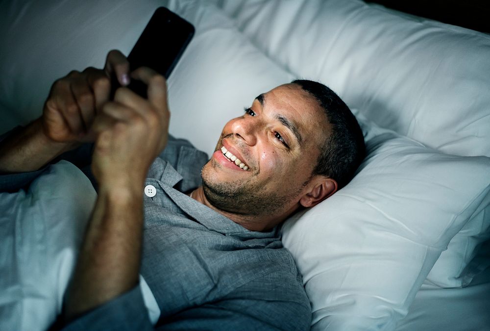 Man using phone on a bed