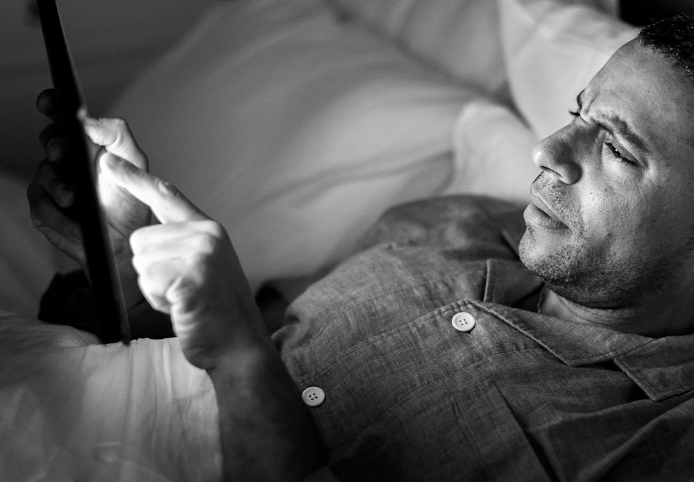 Man using phone on a bed