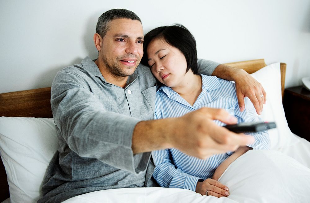 A couple watching tv together in bed