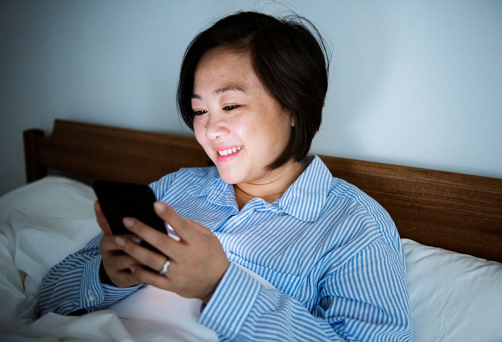 A woman reading from a phone  in bed