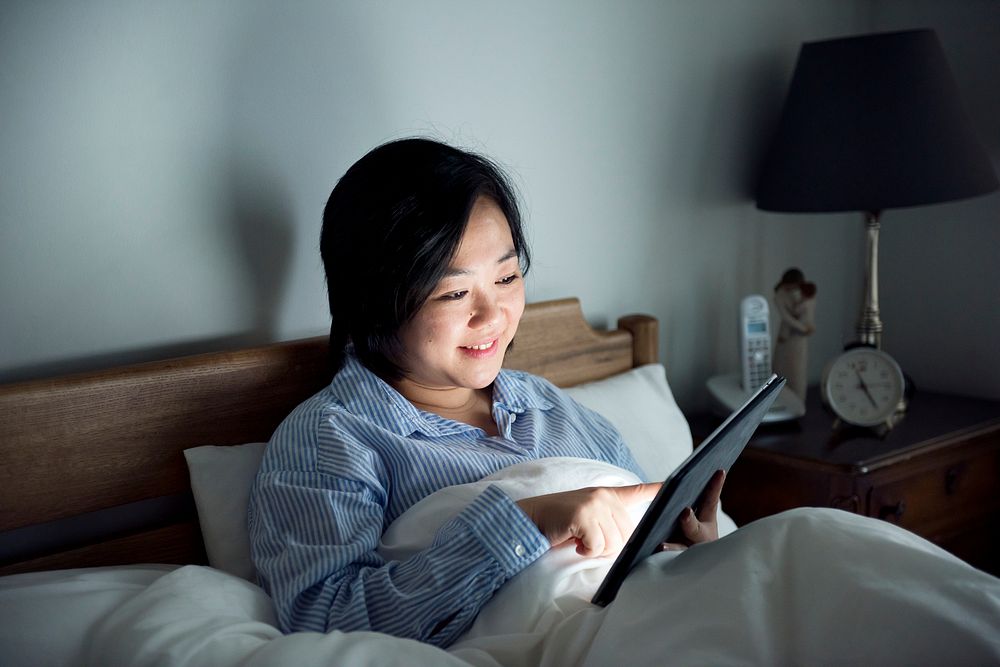 A woman using a tablet in bed
