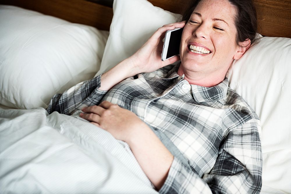 A woman calling someone in bed