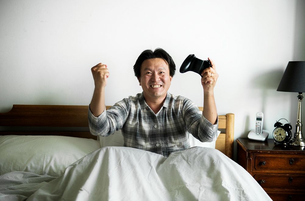 A man playing a video game in bed