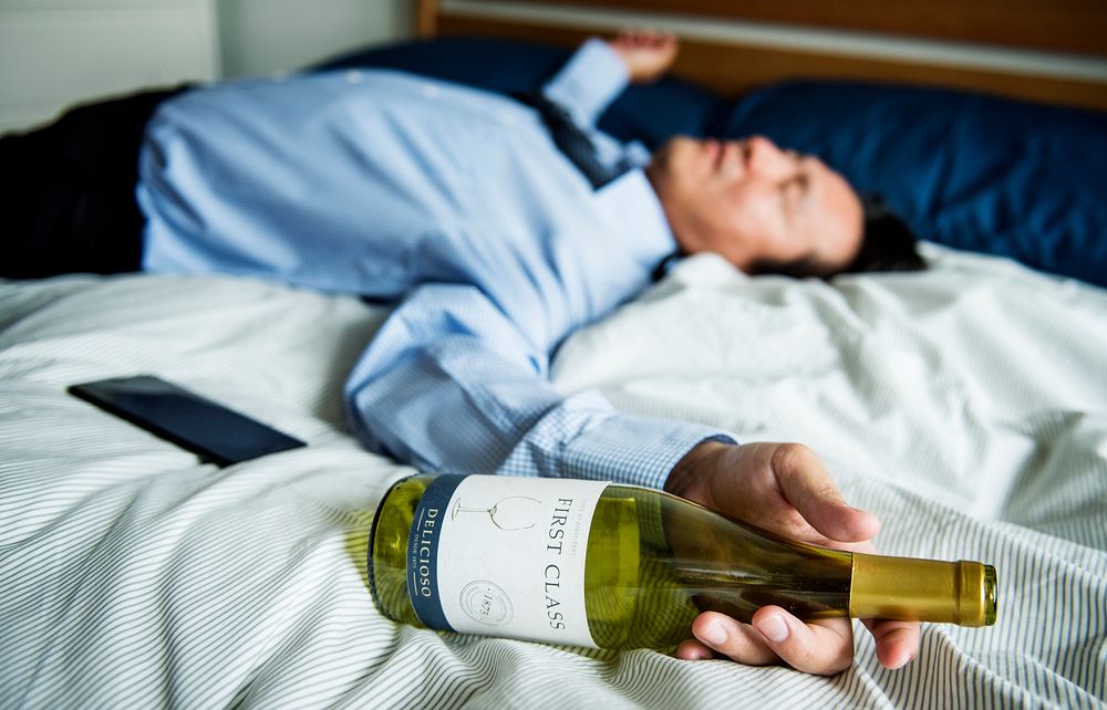 A drunk businessman passing out in bed