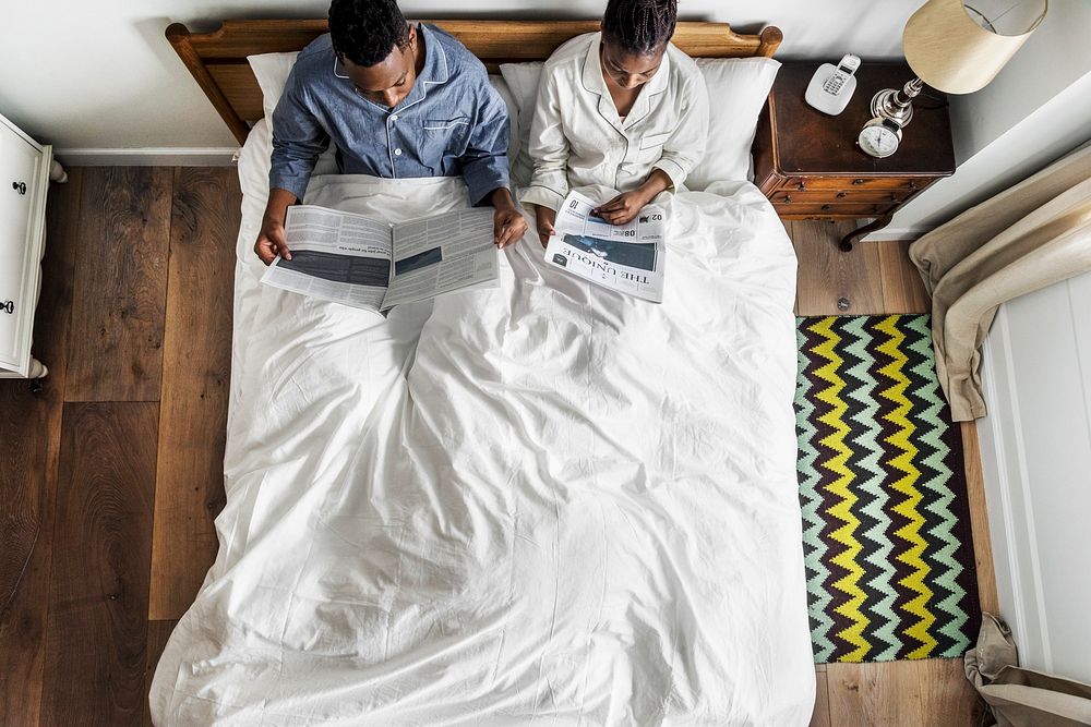 African American couple on bed reading newspapers