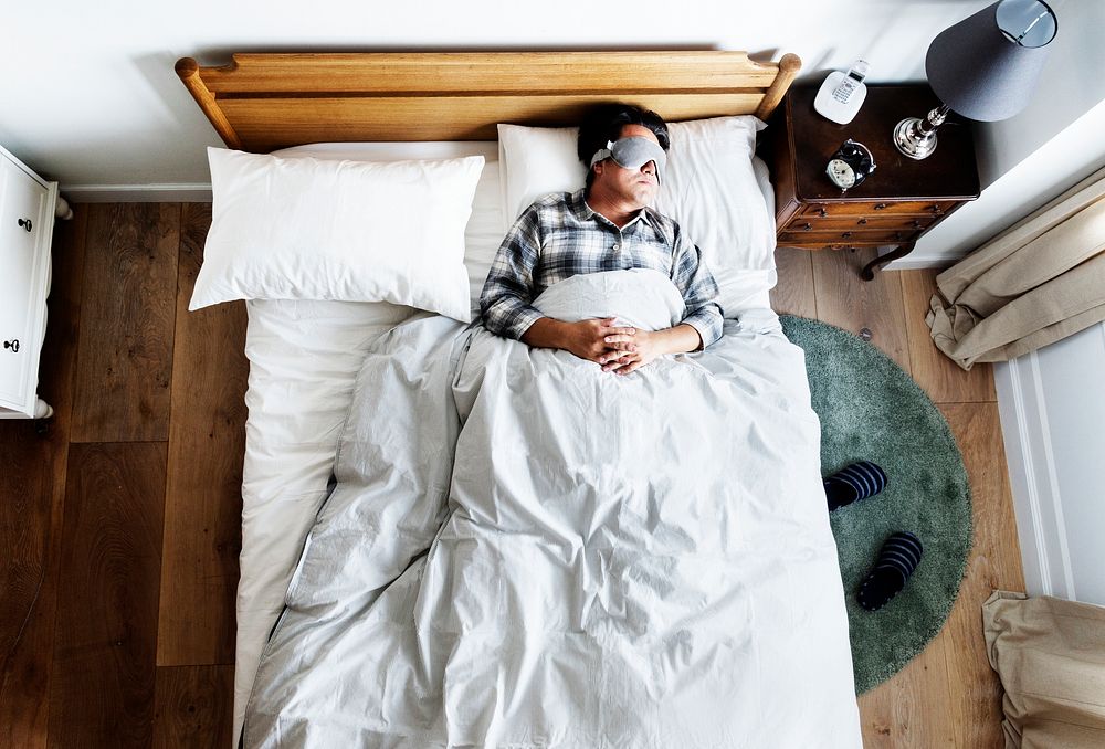 Japanese man sleeping on bed with eye mask