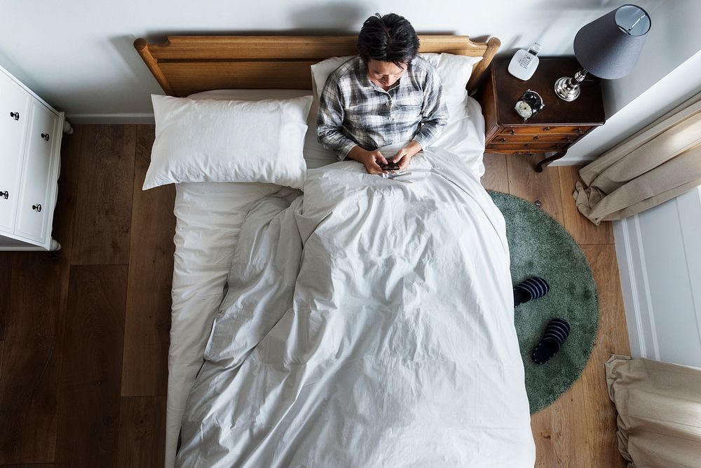 Asian ethnicity guy using phone on the bed