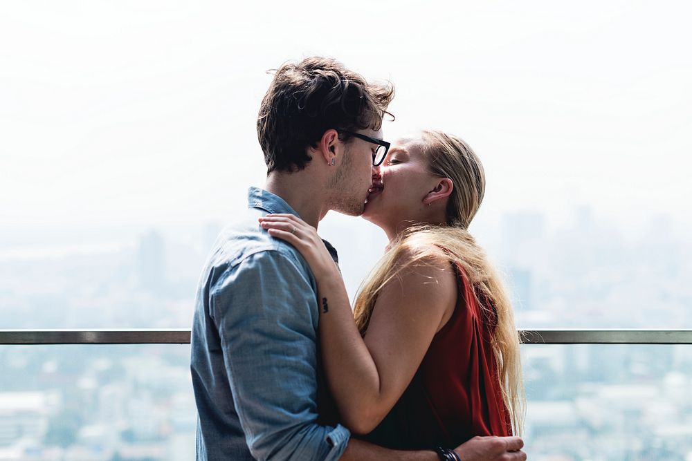 Caucasian couple kissing each other in a cityscape background