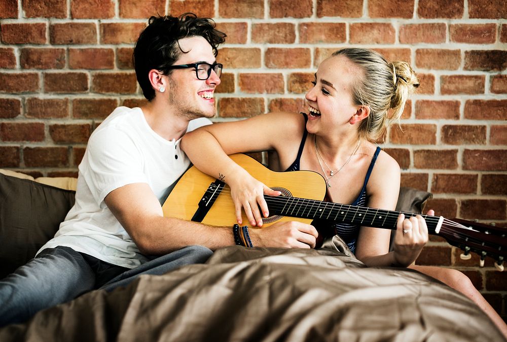 Caucasian couple playing guitar together