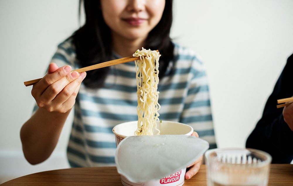 Asian woman eating an instant noodle