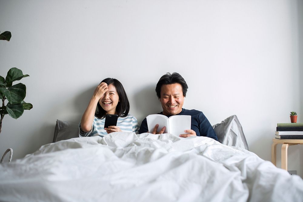 Asian couple relaxing on bed together