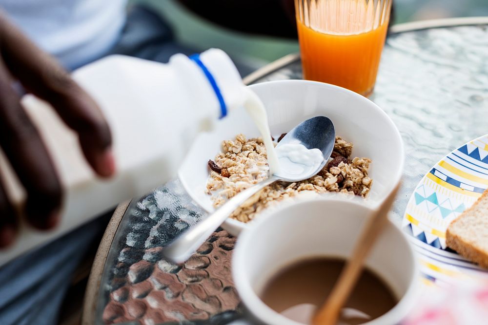 Closeup of hand pouring milk into cereal